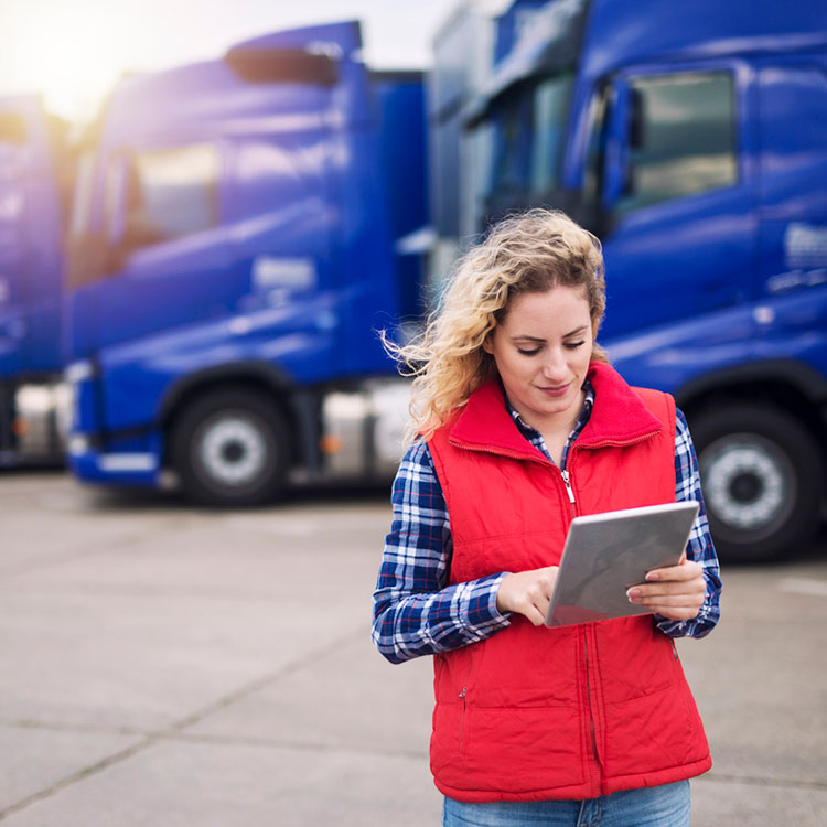 Woman on typing on an iPad in front of a truck.