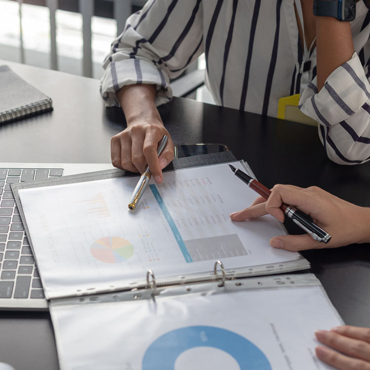 Two coworkers sitting at a table looking at a graph on paper.