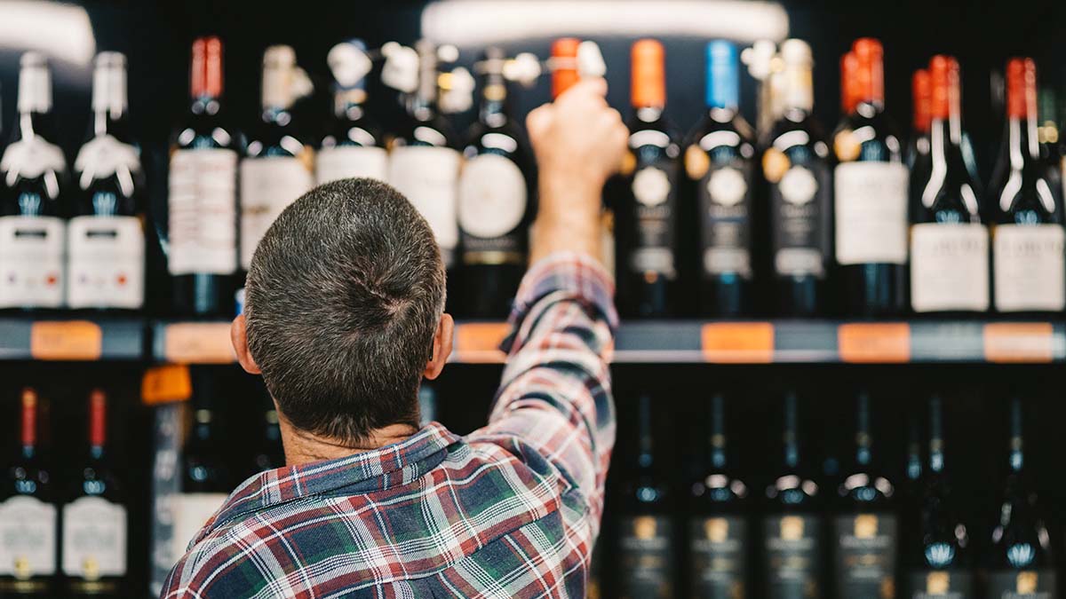 Customer picking up a bottle of wine off the shelf.