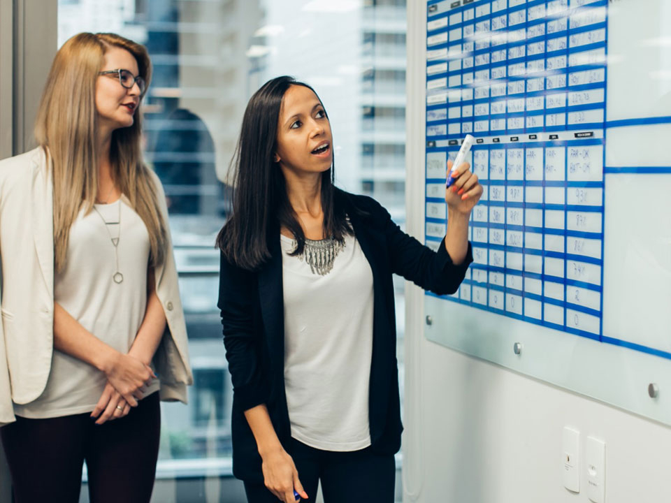 Female presenter at a white board | Managed Services by TMC a division of C.H. Robinson